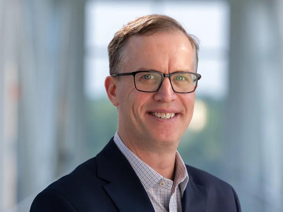 David Miller wearing glasses and blue jacket smiling  